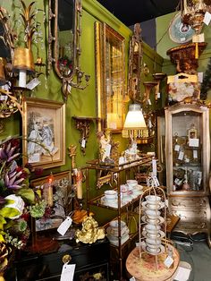 a room filled with lots of different types of items and decor on display in front of green walls