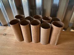 six rolled up toilet paper tubes sitting on top of a wooden table next to a metal wall