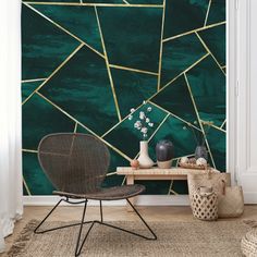 a room with a chair, table and vases on the floor in front of a green wall