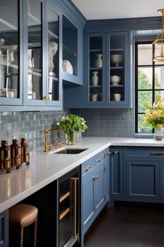 a kitchen with blue cabinets and white counter tops, gold accents on the trimmings