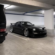 two cars parked in a parking garage next to each other on the floor and one is black