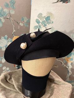 1930 Du Barry hat with tag attached. Black felt combined with grosgrain ribbon held by a, unique, 2 large, baroque, pearls with rhinestone circles. The front brim has a 2 inch slice that is folded back, simple, but, brilliant! The grosgrain ribbon band inside the hat is double in front which allows the first layer to fold down and be worn across the forehead. These design elements make Du Barry hats such fun to wear. 22" Pearl Pin, Black Felt, Grosgrain Ribbon, Design Elements, Caps Hats, Accessories Hats, Tags, Ribbon, Felt