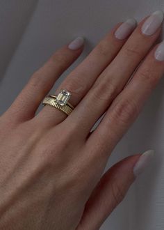 a woman's hand wearing a gold ring with a diamond in the middle and two rows of diamonds on each band