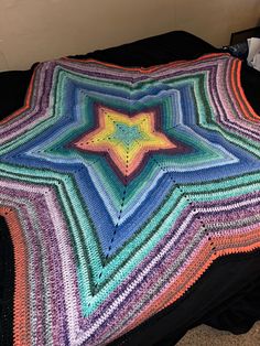 a multicolored crocheted blanket sitting on top of a bed