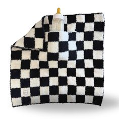 a black and white checkered blanket with a bottle in it's holder on top