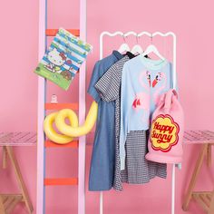 a pink wall with clothes and toys hanging on it