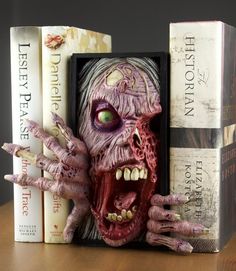 a bookend with an image of a zombie head on it's face and two books behind it