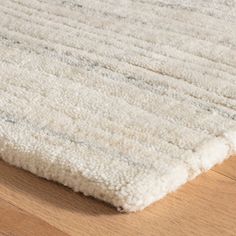 a white rug on top of a wooden floor next to a wood flooring board