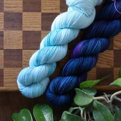 three skeins of blue and purple yarn sitting on top of a wooden table