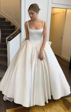 a woman in a white dress is standing near stairs