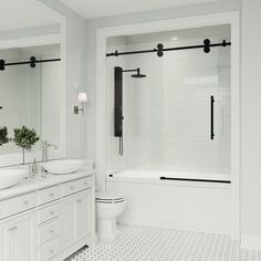 a white bathroom with two sinks and a large mirror over the bathtub is shown