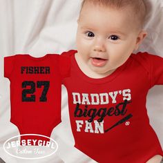 Now your littlest fan can cheer on his or her favorite baseball player with our custom "Daddy's Biggest Fan" baseball infant bodysuit or toddler shirt! Personalize the back of your "Daddy's Biggest Fan" baseball bodysuit or toddler shirt with your baseball player's name and number. Choose your design colors to match your baseball team colors. Or customize this baseball daughter or son shirt however you choose! Enter your personalization under "Add your personalization." Front: specify any changes to the wording, "Daddy's Biggest Fan," if applicable.  Back: enter the baseball player's last name and number exactly as it should appear on the back of your "Daddy's Biggest Fan" bodysuit/shirt. Enter 2 glitter colors: one for "Daddy" and "fan" on the front; and 1 for "biggest" and the baseball b Casual Onesie With Letter Print For Game Day, Cotton Onesie With Letter Print For Sports Events, Bodysuit Shirt, Custom Tees, Baseball Shirts, Baseball Players, Gender Neutral Baby, Team Colors, Baby Bodysuit