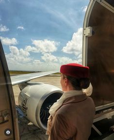 a woman standing in front of an airplane looking out the window