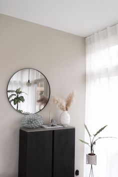 a white room with a black cabinet and round mirror