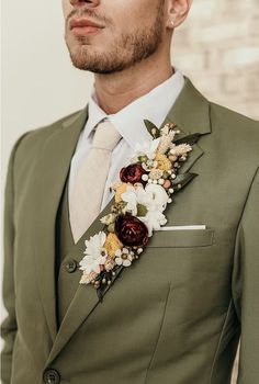 a man wearing a green suit and flower boutonniere