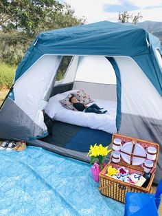 a person laying in a tent on top of a blue blanket