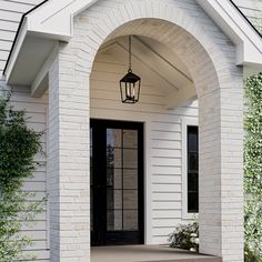 a white house with a black door and light hanging from it's side entrance