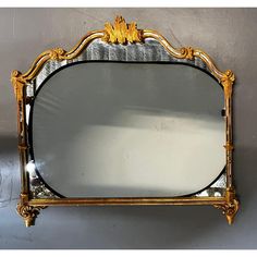 an ornate gold framed mirror against a gray wall