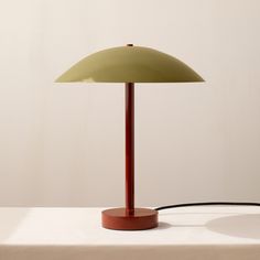 a table lamp sitting on top of a white table next to a brown and black cord