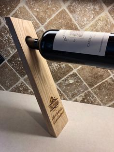 a bottle of wine sitting on top of a wooden stand next to a tile wall