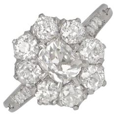 An exquisite cluster engagement ring boasts an elongated antique cushion-cut center diamond, weighing around 0.65 carats. The center diamond is embraced by a cluster of old European cut diamonds. Hand-crafted in platinum, this ring maintains a low profile. The cluster of old European cut diamonds enveloping the center stone totals approximately 1.20 carats. With an overall diamond weight of around 1.85 carats, this ring exhibits I color and VS1-VS2 clarity. Ring Size: 6.5 US, Resizable Color: I Antique Cushion Cut Diamond, Antique Cushion Cut, Antique Cushion, Diamond Cluster Engagement Ring, Cushion Cut Diamond, Cluster Engagement Ring, Cushion Cut Diamonds, European Cut Diamonds, Stone Cuts