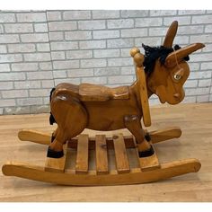 a wooden rocking horse with black hair on it's head