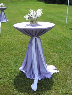 the table is covered with purple cloths and white flowers