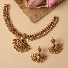 Description : This statement necklace is from Tarinika's festive collection- Indian traditional antique jewelry carved with bedazzled semi-precious kempu stones. Styled with simple yet gorgeous floral motifs and Lakshmi coin patterns this is ideal for bridal events or festive occasions. Details & Specifications: Materials used: Brass Alloy with Antique Plating Weight – Necklace 46.56 gm, Earrings 18.45gm Length – Necklace 15 cm, Earrings 4.5 cm Make it custom Want to make it a custom necklace? S 35grams Gold Necklace Designs, Luxury Gold Temple Jewelry Sets, Semi Precious Stone Jewelry Necklace, Elegant Necklaces With Zari Work For Rituals, Kundan Necklace With Zari Work For Rituals, Traditional Ruby Necklaces For Diwali, Traditional Ruby Necklace For Diwali, Festive Temple Jewelry Kundan Necklace With Intricate Design, Kundan Temple Necklace For Celebrations