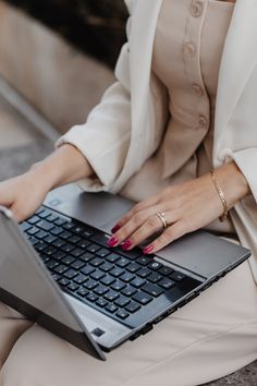 a woman sitting on the ground with her laptop computer in front of her, she is typing