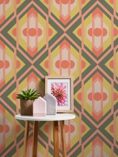 a small table with a potted plant on it next to a wallpaper design