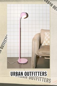 a pink floor lamp sitting on top of a table next to a chair and pillow