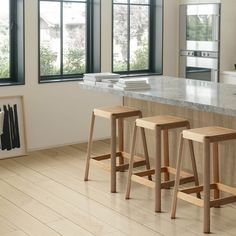 two wooden stools sitting in front of a kitchen counter top next to a window