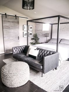 a bedroom with a bed, couch and ottoman