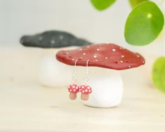 two red mushrooms with white dots on them sitting on top of a mushroom shaped table