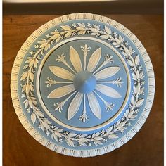 a blue and white plate with flowers on it sitting on top of a wooden table