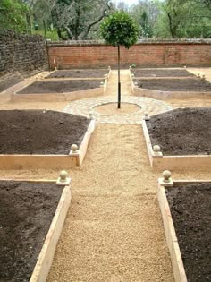 an outdoor garden with many different types of plants and dirt on the ground in front of brick walls