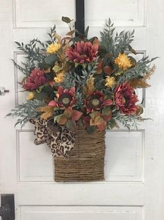 a basket filled with lots of flowers sitting on top of a white door handle next to a leopard print pillow