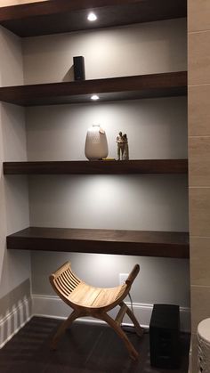 a wooden chair sitting on top of a hard wood floor next to a shelf filled with vases