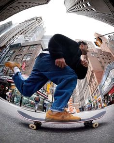 a man riding a skateboard down a street next to tall buildings in a city