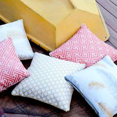 four different colored pillows sitting on top of a wooden floor next to a yellow box