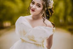 a woman in a white dress is posing for a photo with trees in the background