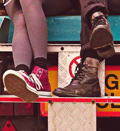 two people sitting on the back of a truck with their feet up and one person wearing red shoes