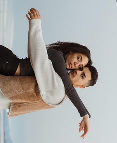 a man and woman standing next to each other with their arms in the air together