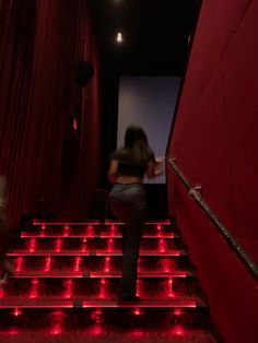 a woman standing on the stairs in front of a projector screen with red lights