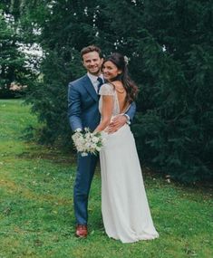 a bride and groom standing in the grass