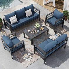 an outdoor patio furniture set with blue cushions and pillows on the floor next to a swimming pool