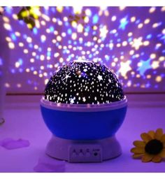 a night sky projector sitting on top of a table next to a yellow flower