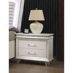 a white lamp sitting on top of a nightstand next to a night stand and mirror