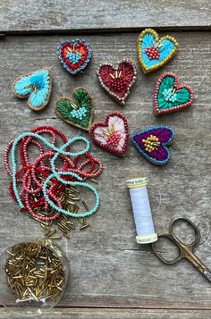 several different types of beading on a wooden surface with scissors and thread in the foreground