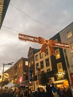 people are walking under a welcome sign at an outdoor christmas market in the city center